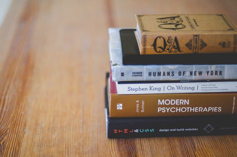A stack of books on a wooden table